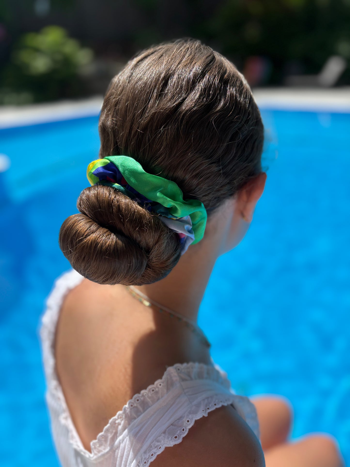 Person with a colorful scrunchie duo in their hair by a pool