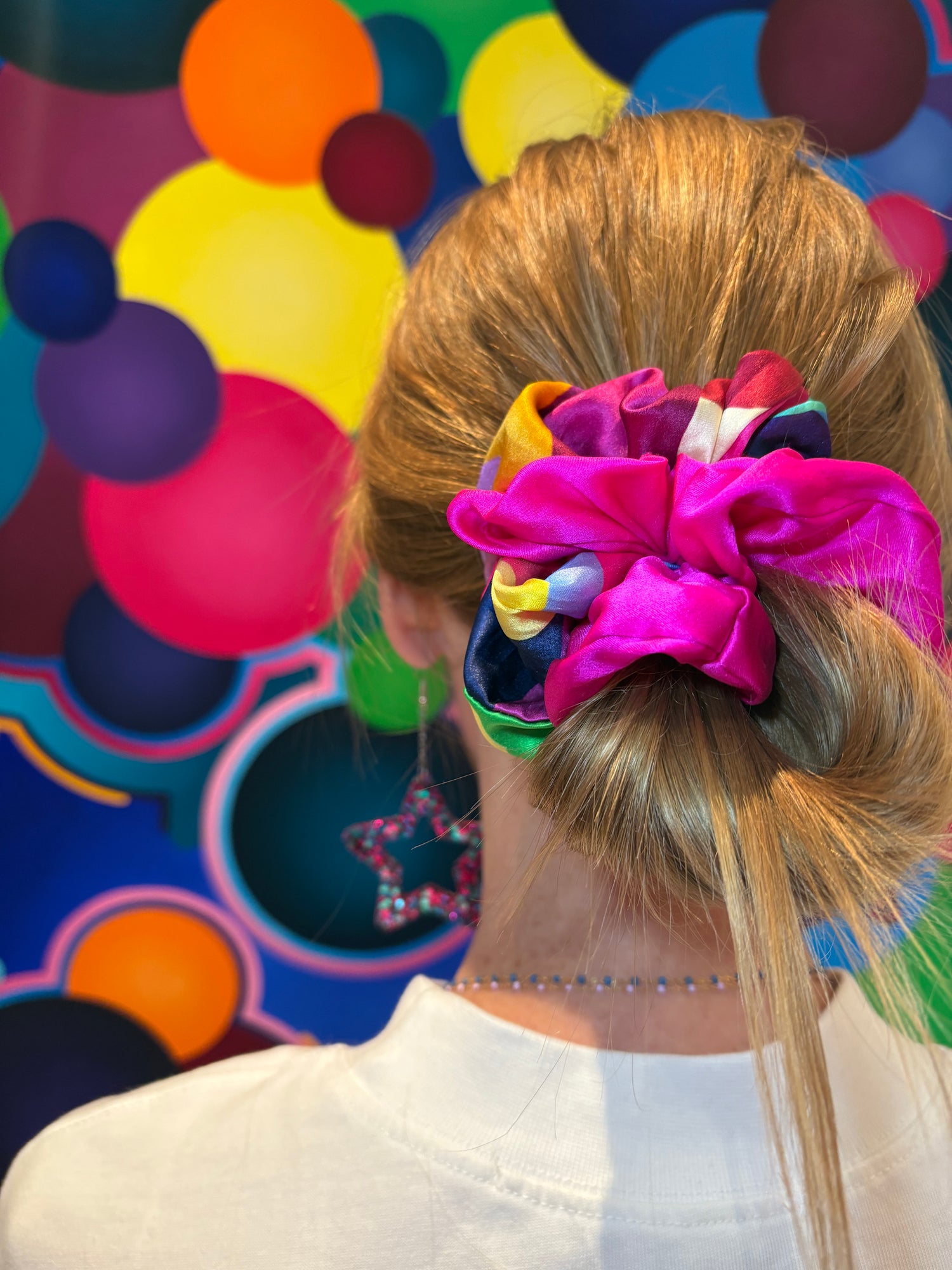 Person with a colorful scrunchie duo in their hair against a multicolored polka dot background