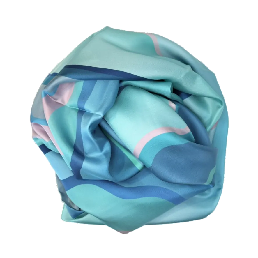 Rolled-up colorful silk scarf with blue, green, and pink patterns on a white background