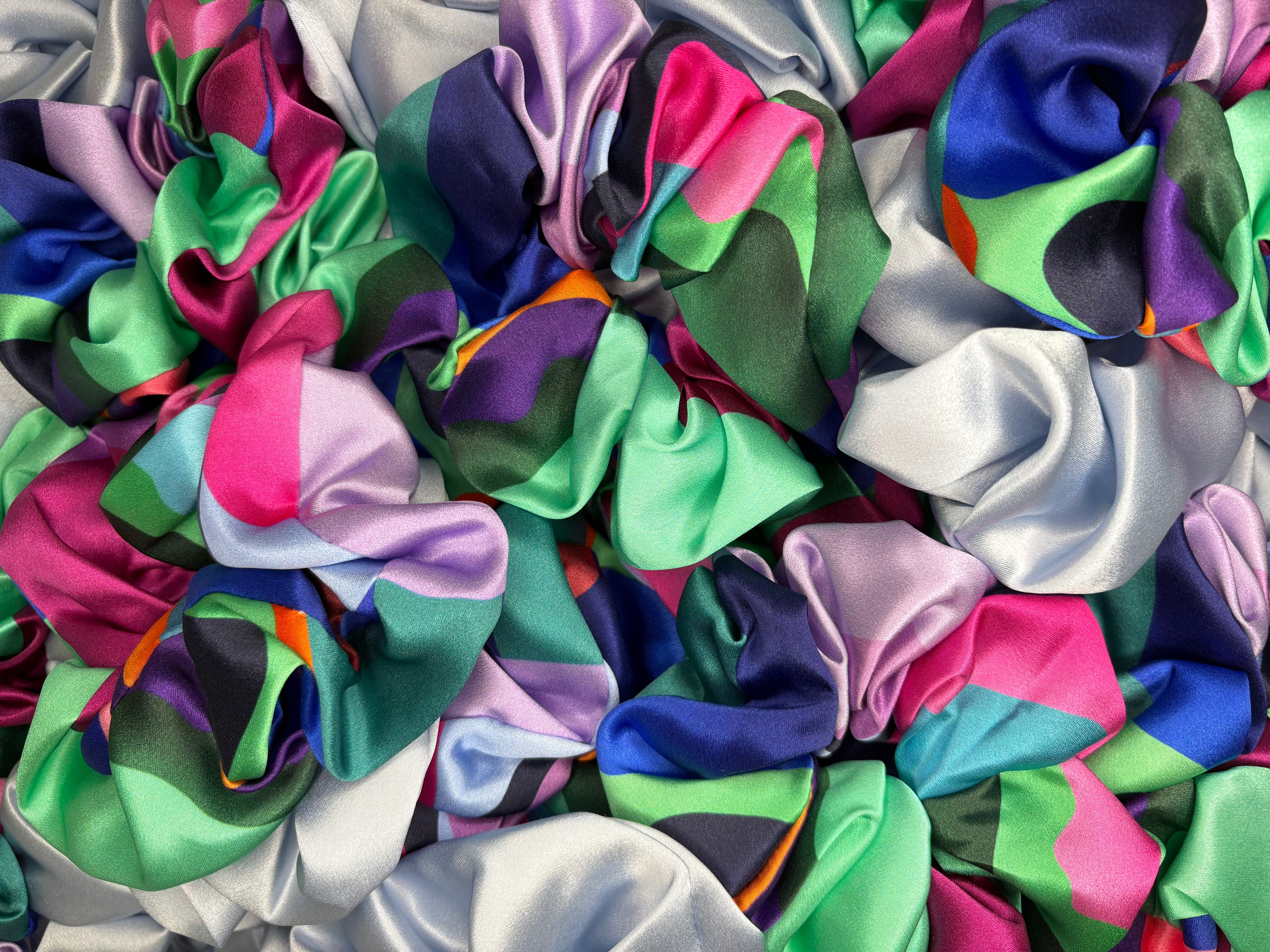 Multicolored scrunchies in various colors including pink, green, blue, and purple.